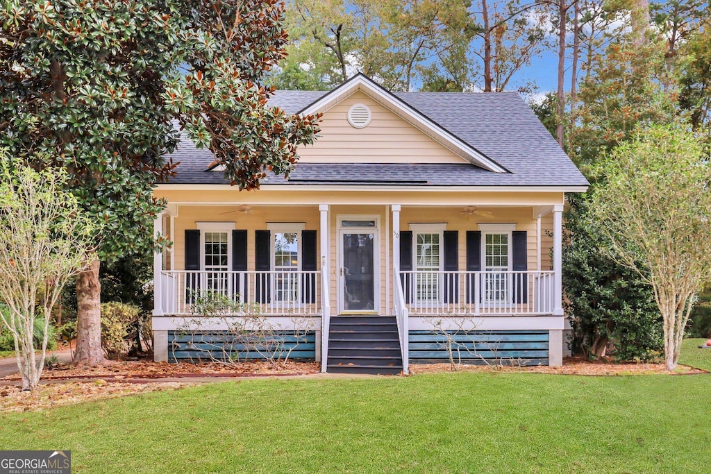 view of front facade with ceiling fan, covered porch, and a front lawn