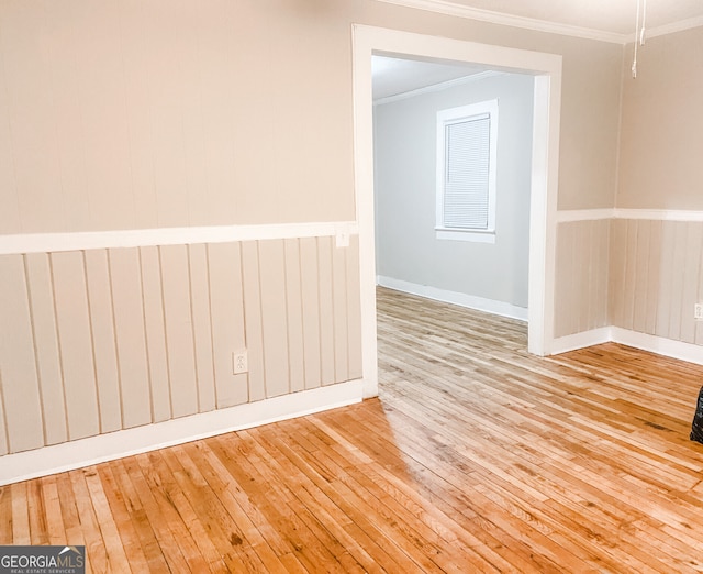 empty room with ornamental molding and light wood-type flooring