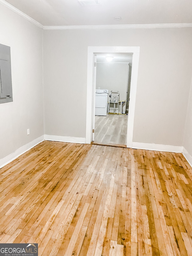 empty room with washer / clothes dryer, wood-type flooring, and ornamental molding