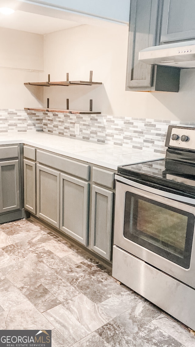 kitchen featuring backsplash, gray cabinets, and stainless steel range with electric cooktop