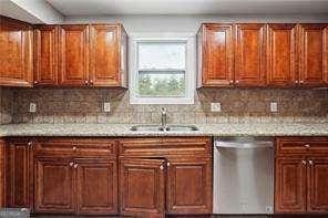 kitchen featuring sink, decorative backsplash, light stone countertops, and dishwasher