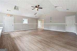 unfurnished living room featuring vaulted ceiling, dark hardwood / wood-style floors, and ceiling fan