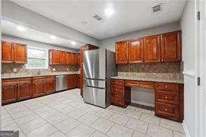 kitchen with tasteful backsplash, light tile patterned floors, built in desk, and stainless steel appliances