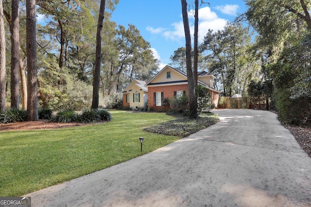 view of front of property featuring brick siding, a front yard, and driveway