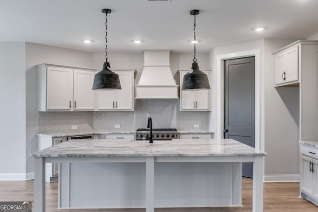 1611 Bethesda Church Rd, Carrollton, GA 30117 - kitchen with custom range hood, tasteful backsplash, decorative light fixtures, light stone counters, and a breakfast bar