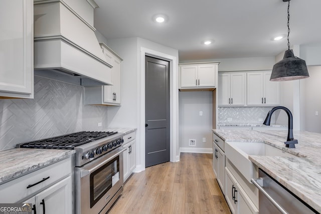 1611 Bethesda Church Rd, Carrollton, GA 30117 - kitchen featuring stainless steel appliances, custom exhaust hood, white cabinets, light wood-style flooring, and pendant lighting