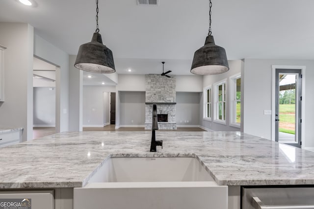 1611 Bethesda Church Rd, Carrollton, GA 30117 - kitchen featuring ceiling fan, a stone fireplace, light stone counters, open floor plan, and hanging light fixtures