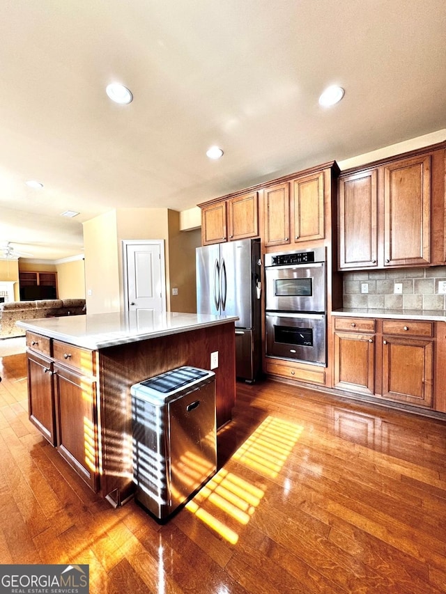 kitchen featuring appliances with stainless steel finishes, a center island, dark hardwood / wood-style flooring, and decorative backsplash