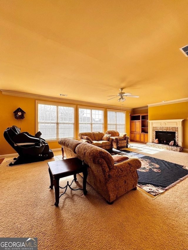 living room featuring crown molding, a fireplace, ceiling fan, and carpet