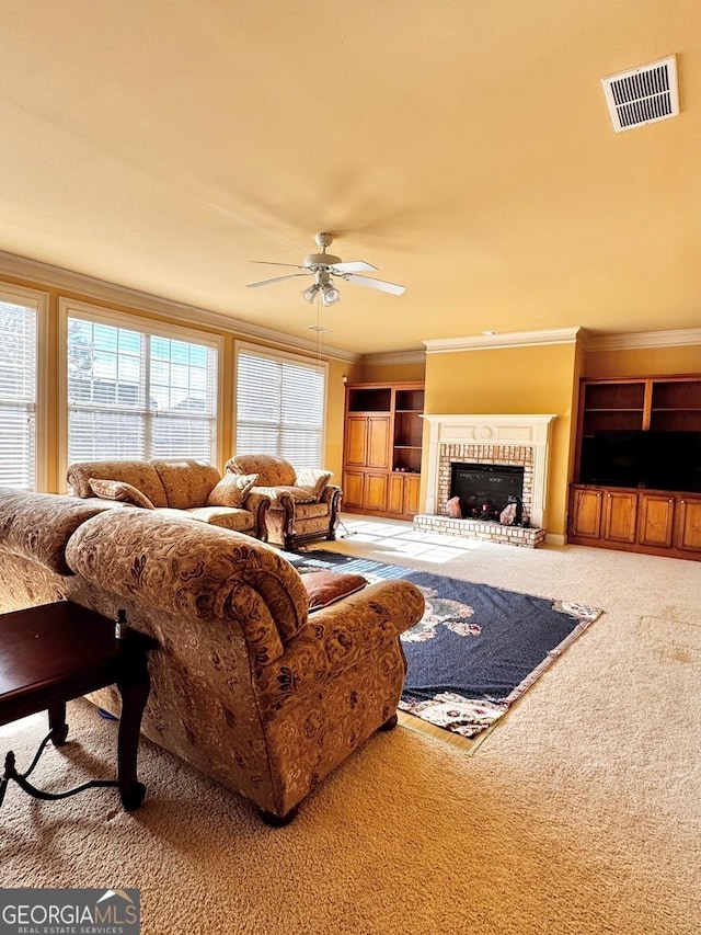 living room with crown molding, a brick fireplace, carpet flooring, and ceiling fan