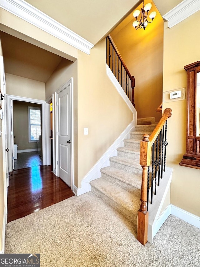 stairs featuring crown molding, carpet flooring, and a chandelier