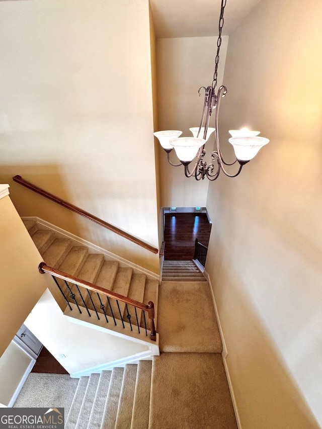 staircase with a notable chandelier and carpet