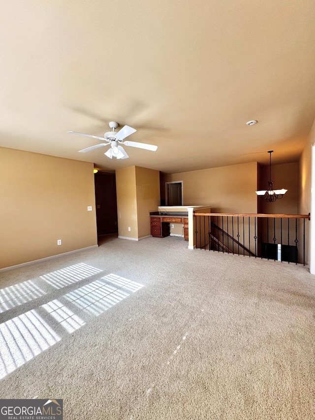 unfurnished living room with ceiling fan with notable chandelier and carpet floors