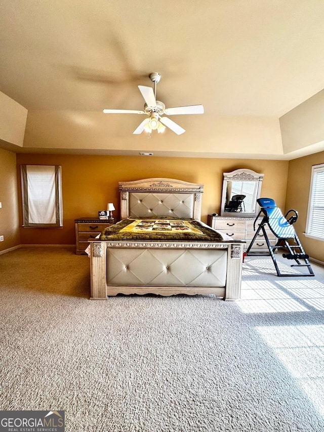 bedroom with light carpet, a tray ceiling, and ceiling fan