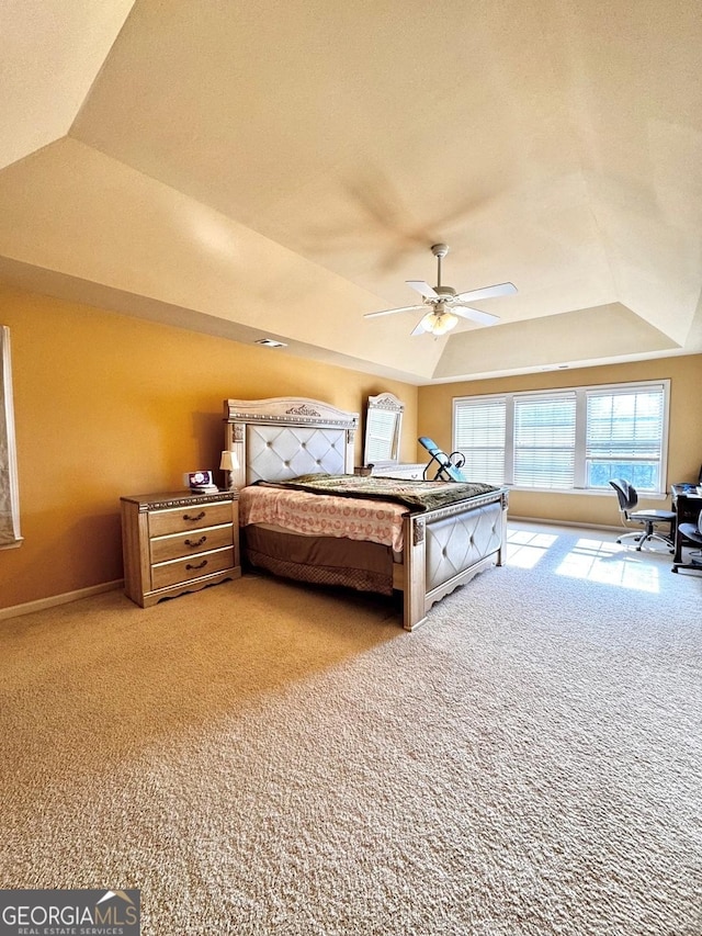 carpeted bedroom featuring a raised ceiling and ceiling fan