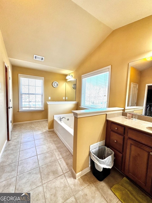 bathroom featuring tile patterned flooring, vaulted ceiling, a tub, and a wealth of natural light