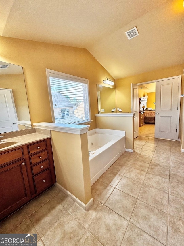 bathroom featuring tile patterned floors, a bathing tub, vaulted ceiling, and vanity