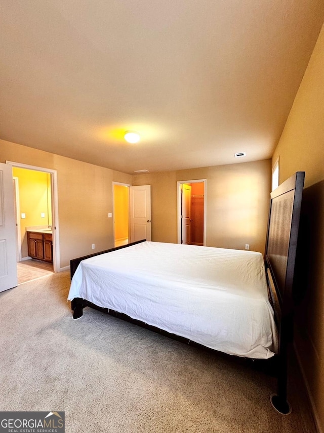 bedroom with connected bathroom and carpet floors