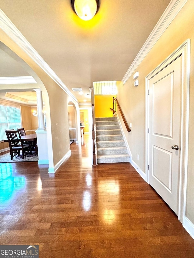 interior space with crown molding, wood-type flooring, and decorative columns