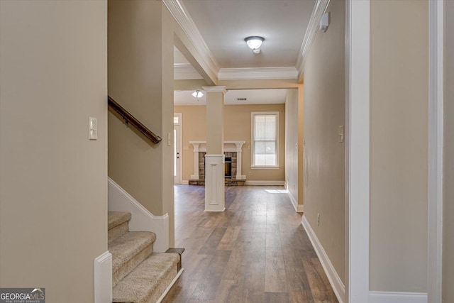 foyer entrance featuring hardwood / wood-style flooring, ornamental molding, a fireplace, and decorative columns