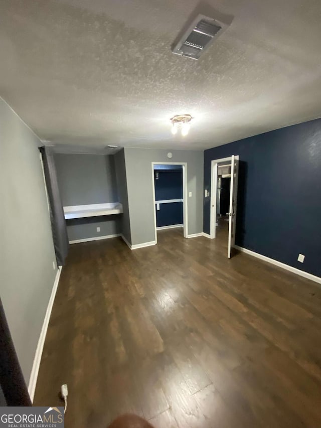 spare room featuring dark hardwood / wood-style floors and a textured ceiling