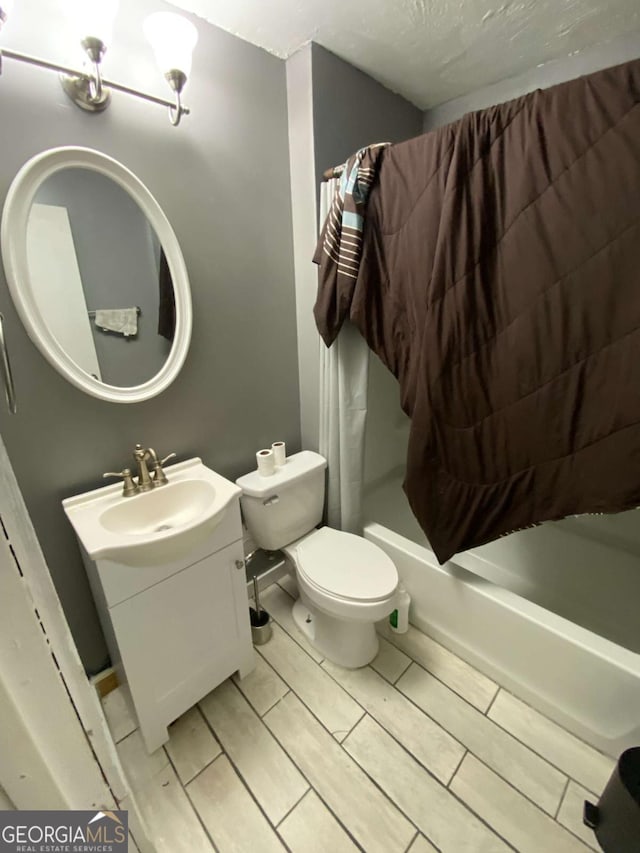 full bathroom featuring vanity, a textured ceiling, toilet, and shower / bath combo with shower curtain