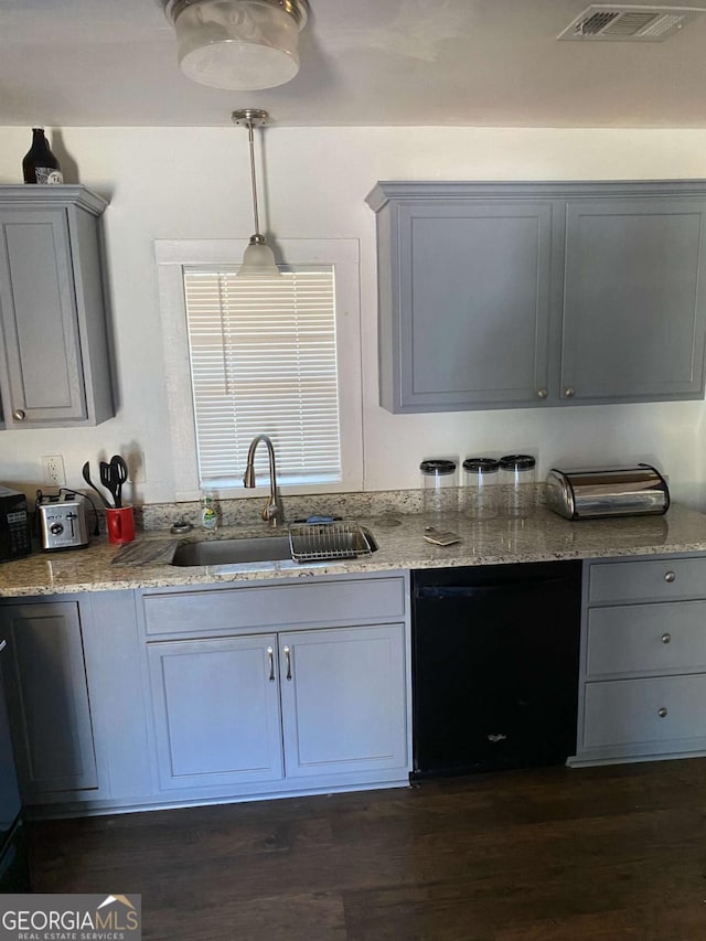 kitchen featuring sink, dishwasher, dark hardwood / wood-style floors, light stone countertops, and decorative light fixtures