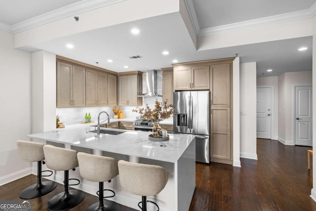 kitchen featuring a breakfast bar, sink, kitchen peninsula, stainless steel appliances, and wall chimney exhaust hood