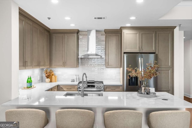 kitchen with sink, stainless steel refrigerator, a kitchen breakfast bar, kitchen peninsula, and wall chimney exhaust hood