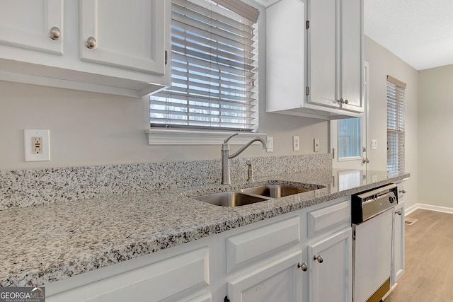 kitchen with sink, light stone countertops, white cabinets, and dishwasher