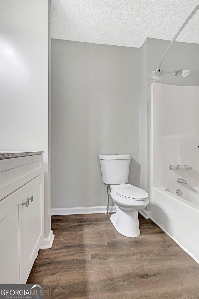 full bathroom with toilet, a textured ceiling, shower / tub combination, vanity, and hardwood / wood-style floors