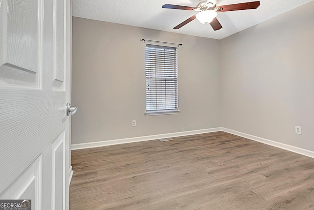 empty room with a textured ceiling, light hardwood / wood-style floors, and ceiling fan