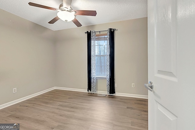 empty room featuring ceiling fan, wood-type flooring, and a textured ceiling