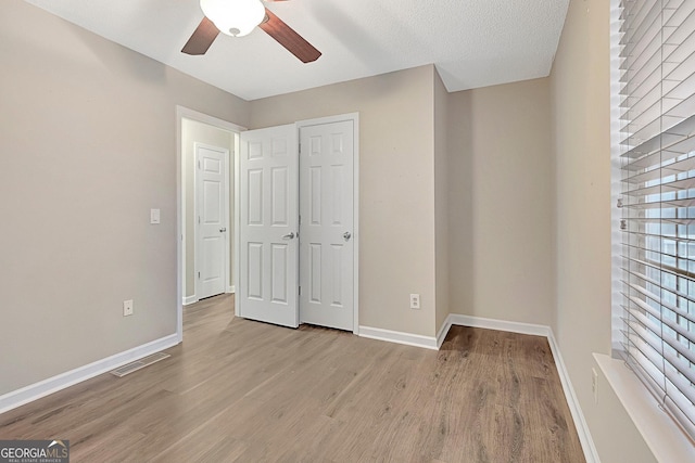 unfurnished bedroom featuring ceiling fan, light hardwood / wood-style floors, and a textured ceiling