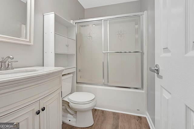 full bathroom featuring vanity, hardwood / wood-style flooring, bath / shower combo with glass door, and toilet