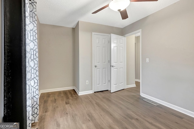 unfurnished bedroom featuring ceiling fan, light hardwood / wood-style flooring, and a textured ceiling