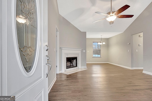 unfurnished living room featuring a high end fireplace, vaulted ceiling, dark hardwood / wood-style floors, and ceiling fan