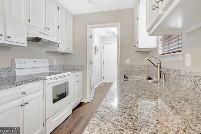 kitchen with electric stove, sink, light stone counters, and white cabinetry