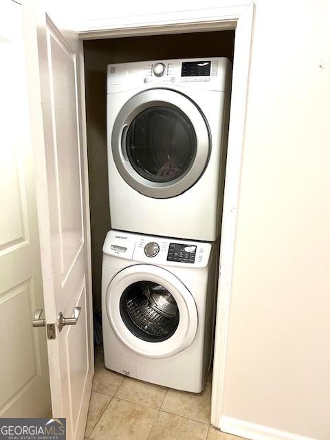 clothes washing area featuring stacked washer / drying machine and light tile patterned floors