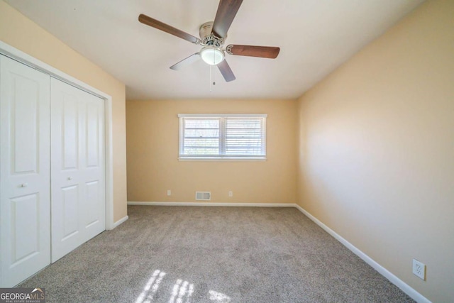 unfurnished bedroom with ceiling fan, light colored carpet, and a closet