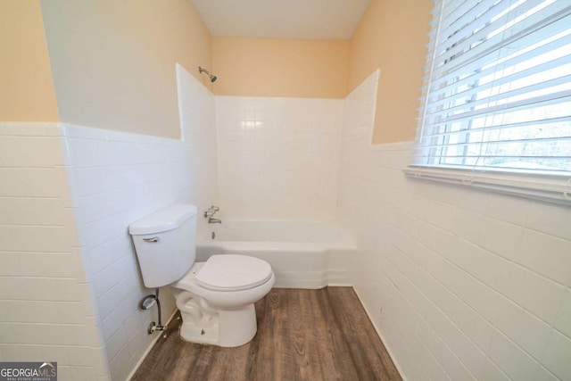 bathroom featuring hardwood / wood-style flooring, toilet, bathing tub / shower combination, and tile walls