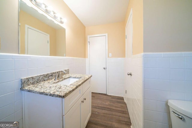 bathroom with hardwood / wood-style floors, vanity, tile walls, and toilet