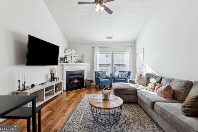 living room featuring wood-type flooring, vaulted ceiling, and a textured ceiling