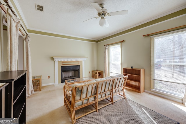 living room with light carpet, ceiling fan, ornamental molding, and a textured ceiling