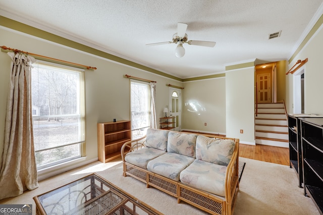 carpeted living room featuring crown molding, a wealth of natural light, ceiling fan, and a textured ceiling