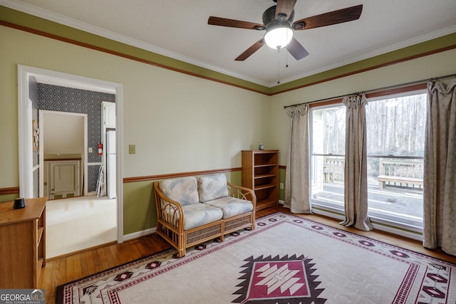 sitting room with wood-type flooring, ornamental molding, and ceiling fan