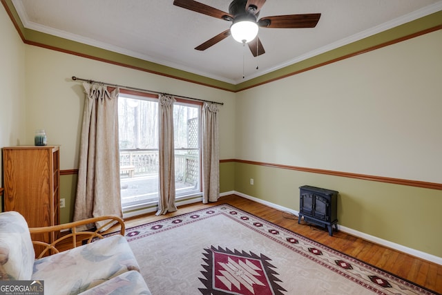 living room featuring hardwood / wood-style flooring, ceiling fan, ornamental molding, and a wood stove