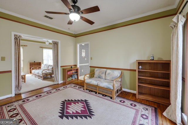 living area with crown molding, hardwood / wood-style floors, and ceiling fan