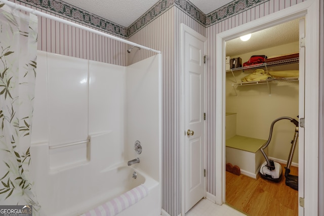 bathroom featuring hardwood / wood-style flooring, shower / tub combo with curtain, and a textured ceiling