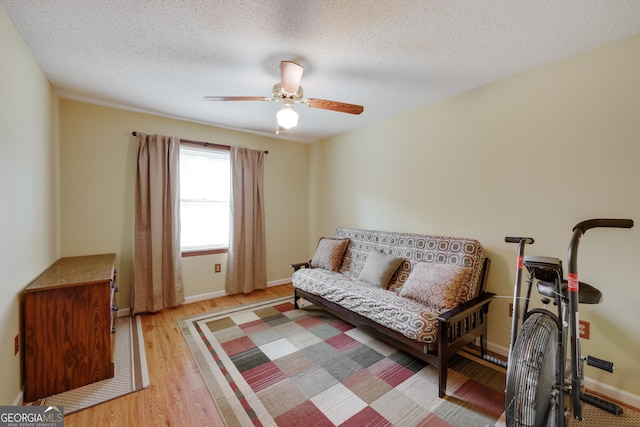 living area featuring ceiling fan, light hardwood / wood-style flooring, and a textured ceiling